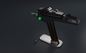 Phaser displayed on magnetic stand with tip glowing green and dilithium crystal inspection chamber door open